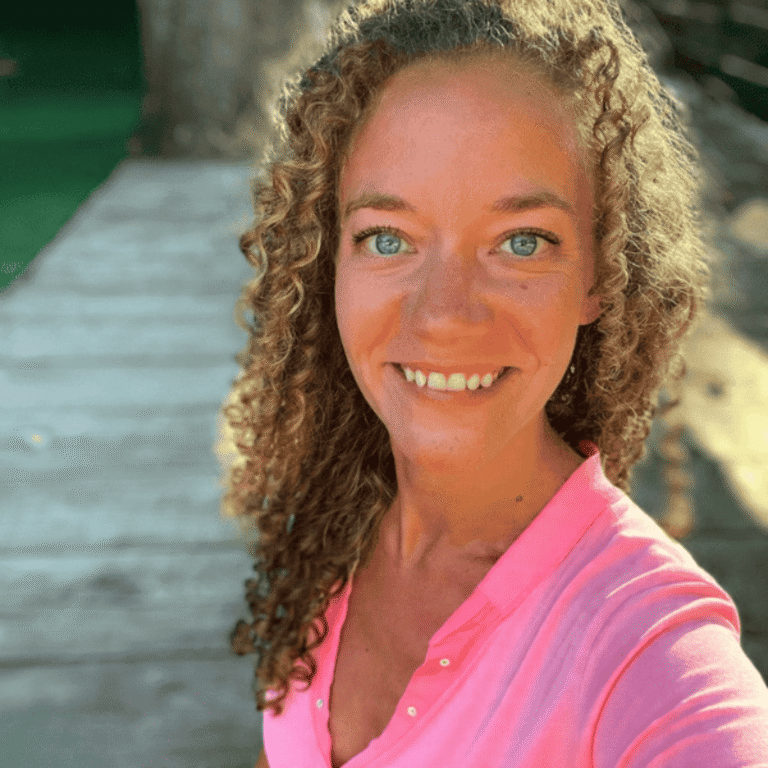 Danielle gray smiling at the camera wearing a pink shirt standing outside in natural light