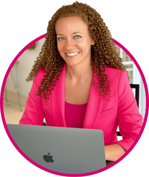 Danielle gray in hot pink blazer smiling while working on her lap top